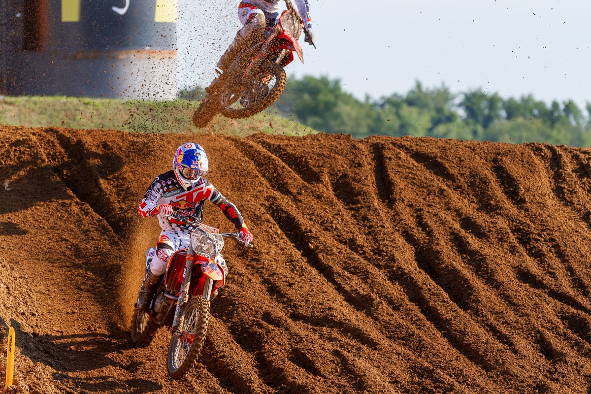 Two motocross riders racing over a jump